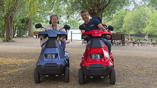 Photo of Councillor Beth Rowland and Councillor Mark Ashwell driving mobility scooters at Dinton Pastures Country Park