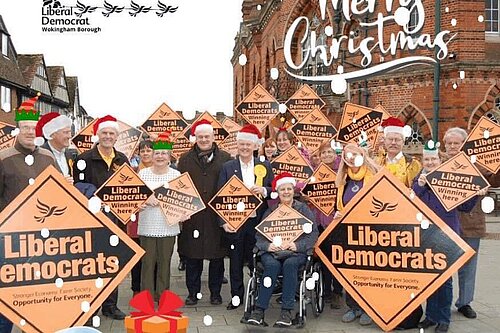 Lib Dems outside Wokingham town hall, with Santa hats, snow ans other Christmas items superimposed on top. The Lib Dem Wokingham logo has been made to look like Santa in his sleigh being pulled by Lib Dem birds