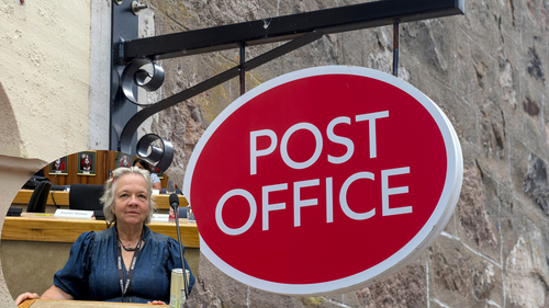 Cllr Jane Ainslie in front of post office sign