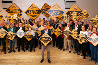 Stephen Conway with lots of Lib Dems with yellow diamond signs behind him