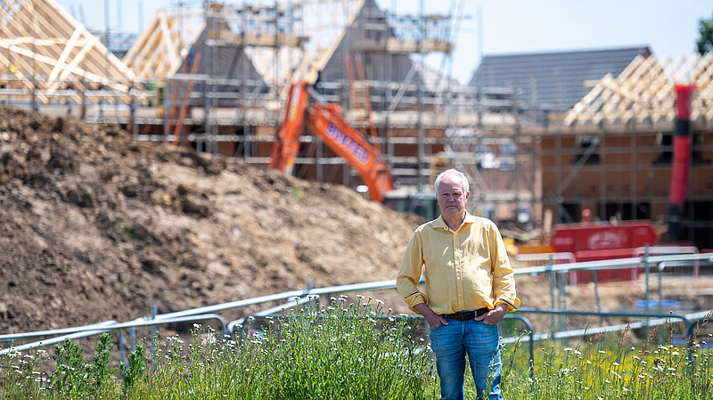 Clive Jones in field with building work in background