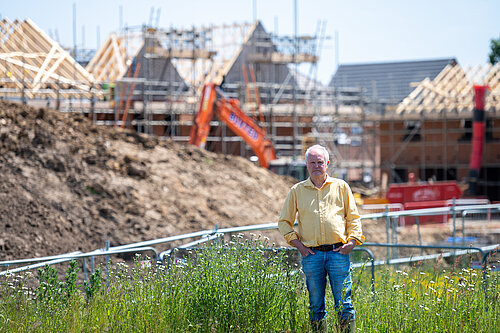 Clive Jones in field with building work in background