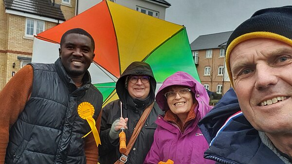 Lib Dems canvassing, smiling under a colourful umbrella